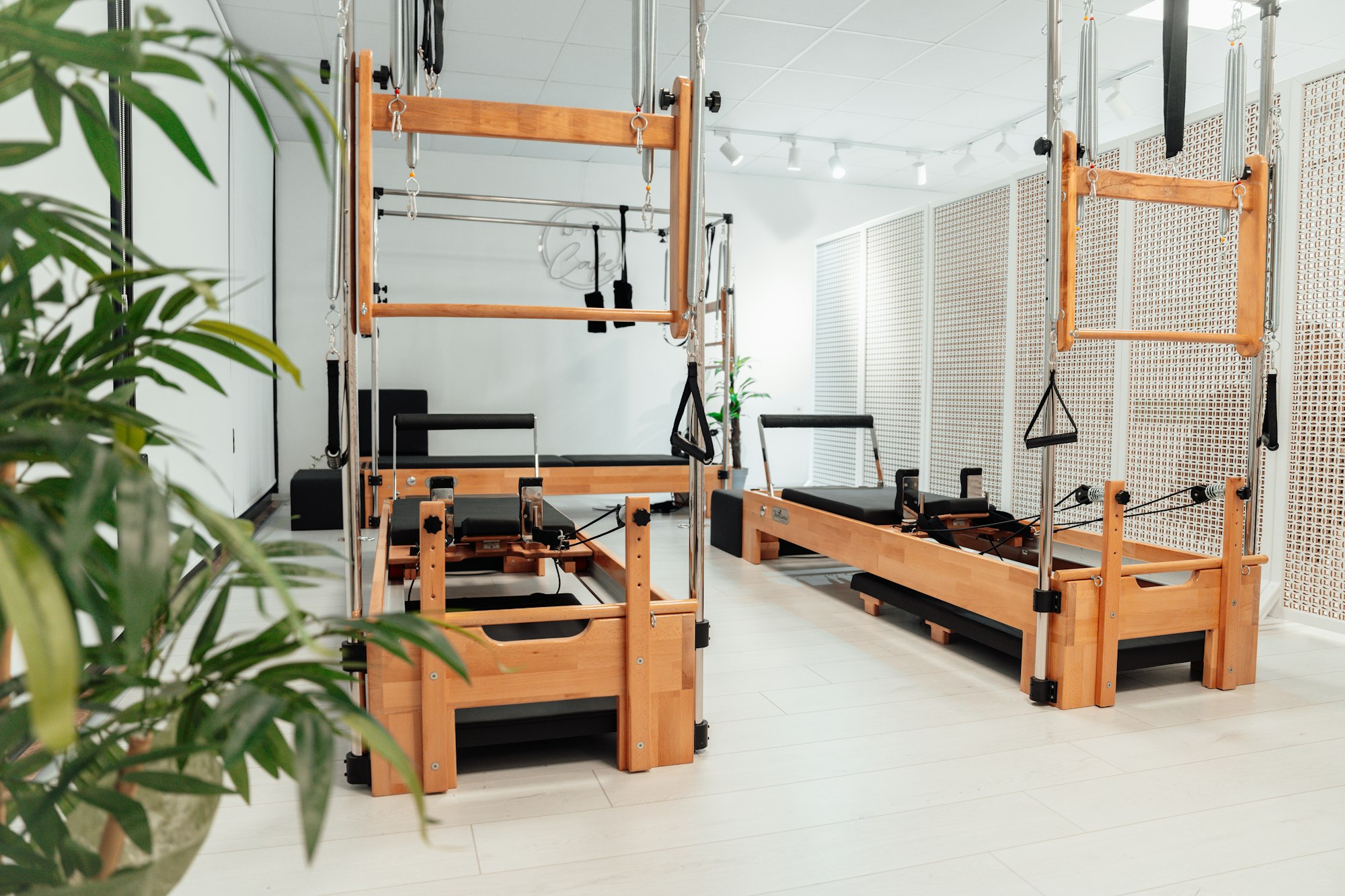 The Su Studio reformer room: oak reformers and towers in a bright white space with plants